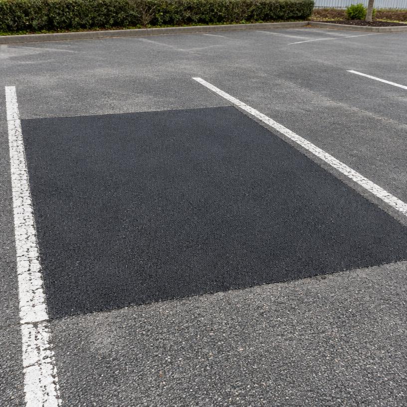 Repaired asphalt within a car park bay