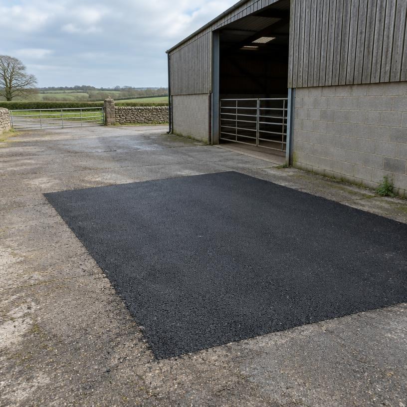 Asphalt repair in a farm yard beside a barn